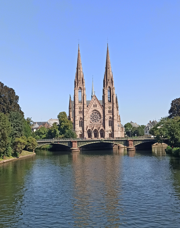 Das Bild zeigt die Îll in Straßburg mit Blick auf eine Kirche, im Vordergrund ist eine Brücke