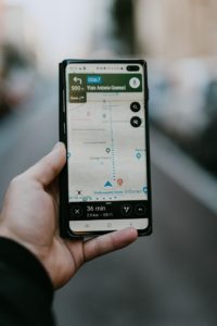 Person hält Handy in der Hand mit einer geöffneten Navigationsapp, die den Weg anzeigt